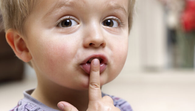 Little boy with finger on his lips.